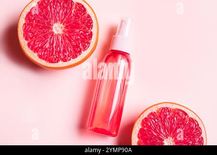 Body mist spray, face mist bottle with grapefruit slices on pink background. Natural cosmetic product with citrus fruit extract. Citrus essential oil, Stock Photo