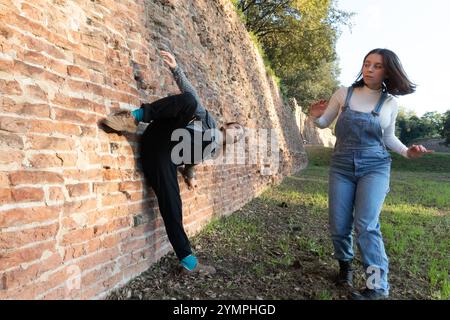 Two dancers performing a modern choreography in an urban setting with an old brick wall Stock Photo