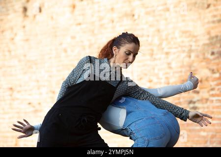 Two female dancers practicing a modern dance choreography against a brick wall Stock Photo