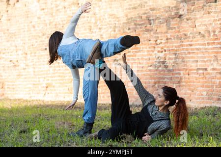 Two female dancers practicing a modern dance choreography outdoors, showcasing flexibility, balance, and creative movement Stock Photo