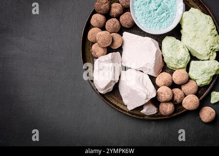 Edible various Clay Stones, clay rocks and powder on black background, top view, copy space.  Natural edible calcium chalk or clay balls. Stock Photo
