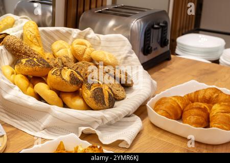 Assorted bread in wicker basket, baguettes. croissants and buns, toaster, hotel breakfast concept Stock Photo