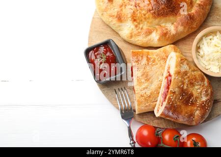 Pieces of fresh calzone pizza served on white wooden table, top view. Space for text Stock Photo