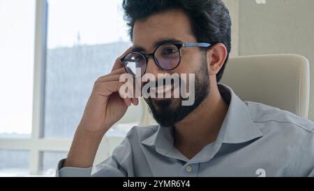 Moving shot Arabian Indian businessman smiling male entrepreneur CEO employer executive manager working with laptop computer typing project at office Stock Photo