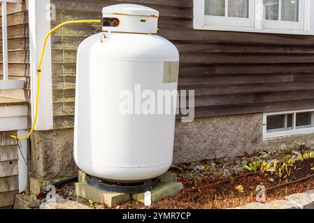 Close up of a white steel propane cylinder against the external wooden wall of a house Stock Photo