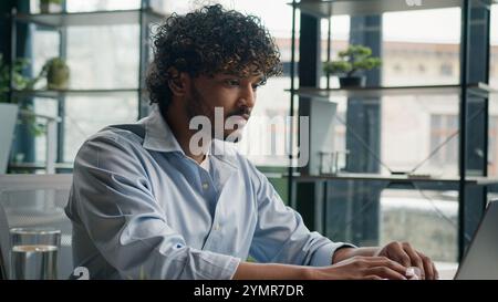 Business portrait Indian arabian man smiling male businessman cheerful guy gen z working on laptop computer studying online at office ethnic hispanic Stock Photo