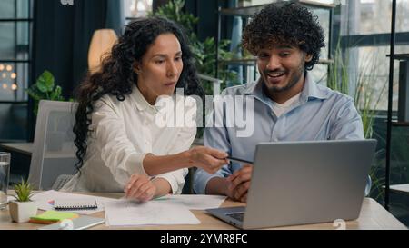 Arabian female employer insurance agent consult Indian male client discuss business project finance marketing data on laptop two multiracial Stock Photo