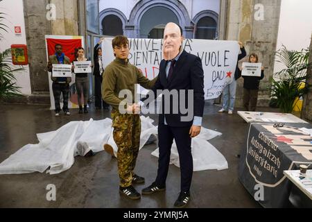 Students against the Nato and University Memorandum A student wore the mask of Rector Roberto Tottoli shaking hands with a boy in uniform who instead portrays Nato commander Angelo Michele Ristuccia. Around them, bodies symbolically stretched out, covered by white sheets, symbolising, the organisers claim, the many victims of armed conflicts, supported by the Atlantic Alliance The students in occupation declare: Our university is currently part of a memorandum of understanding with two NATO commands, with the Vittorio Veneto Division Command and the future Command of the Multinational Division Stock Photo