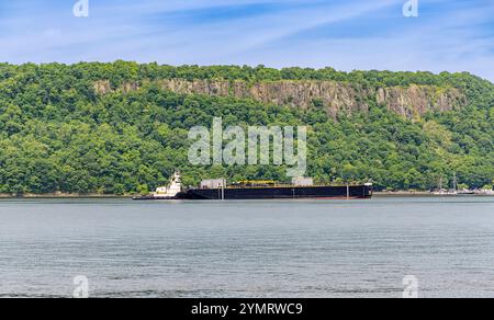 river tug boat pushing a large barge on the hudson river with the palisades in the background Stock Photo