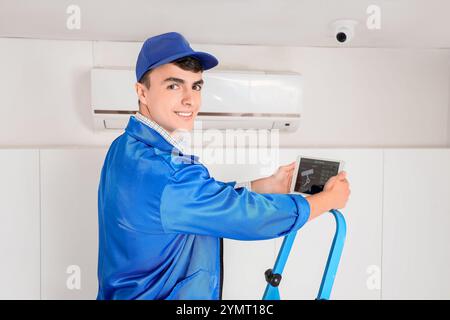 Male worker with tablet installing alarm system in house Stock Photo