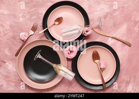 Set of beautiful tableware and flowers on pink grunge background Stock Photo