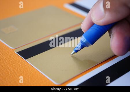 This is the process of Hand Writing on Luxury Gold Credit Cards using a Blue Ink Pen Stock Photo