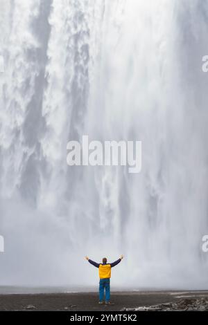 Man at Skógafoss Waterfall.  Skógar, Southern Region, Iceland Stock Photo