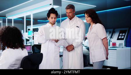 Medical Research Laboratory. Employees Talking In Lab Using Laptop Stock Photo