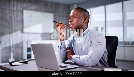 African American Using Online Time Sheets On Computer And Phone Stock Photo