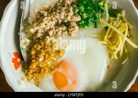 Hot Chinese congee (rice porridge) with minced pork on wooden table for street food Asia concept Stock Photo