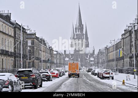 Edinburgh, Scotland, UK. 23rd Nov 2024. Storm Bert:Heavy snow in the West End part of the city at Melville Street disrupts cars and pedestrians temporarily. Snow persists in the West End longer than anticipated. Looking along Melville street towards St. Mary's cathedral covered in snow.  Credit: Craig Brown/Alamy Live News Stock Photo