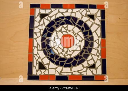 A roundel mosaic made using ceramic tiles, tile grout and plywood. The mosaic is leaning against a piece of plywood after being completed. Stock Photo
