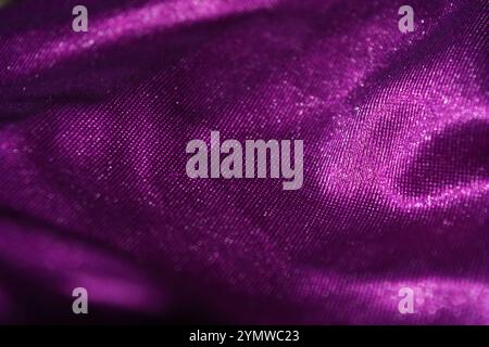 Fabrics, clothes, things, objects, dark purple backgrounds. Beautiful bright velvety purple fabric with interesting shimmer, reflection. Stock Photo