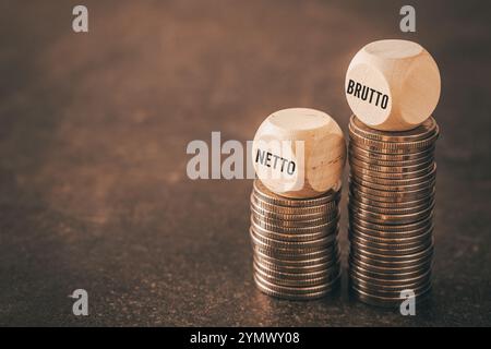 Netto and brutto. Net and gross symbol. Words on wooden cubes set on smaller and larger stack of coins change net to gross. Financial concept, dark wo Stock Photo