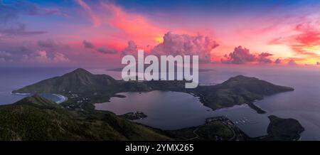 Dramatic sunset over St Kitts, Christophe Harbor colorful sun rays painting the clouds pink, red and purple as the sun sets over Nevis peak Stock Photo