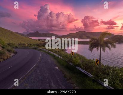 Dramatic sunset over St Kitts, Christophe Harbor colorful sun rays painting the clouds pink, red and purple as the sun sets over Nevis peak Stock Photo