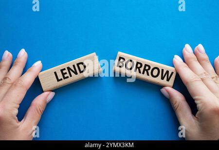 Lend or Borrow symbol. Concept word Lend or Borrow on wooden blocks. Businessman hand. Beautiful blue background. Business and Lend or Borrow concept. Stock Photo