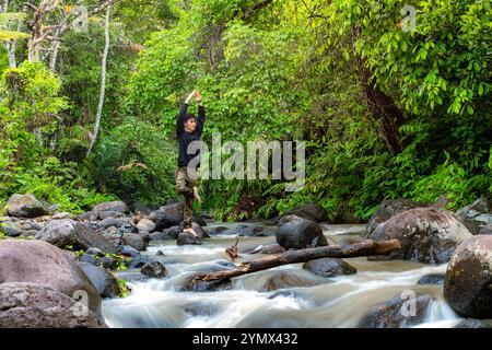 Young man practicing yoga poses near the river. Handsome man doing meditation in the serene forest Stock Photo