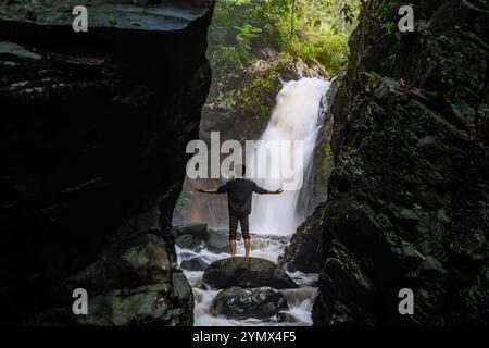 Man standing in front of beautiful Waterfall. Beautiful landscape with waterfall and cliff scenery Stock Photo