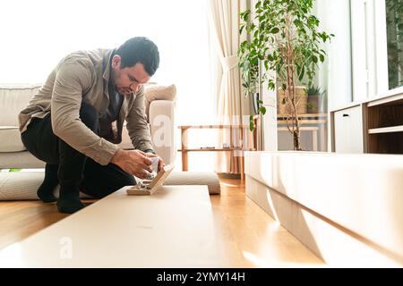 Man in a new home who assembles furniture for self-assembly.Professional Furniture Assembly Worker Assembles Shelf. Professional Handyman Doing Assemb Stock Photo