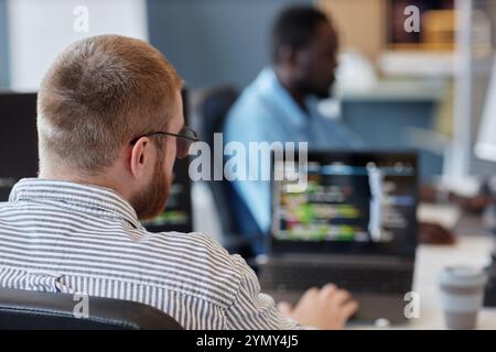 Portrait of developer concentrating on computer screen while coding in collaborative office space Stock Photo