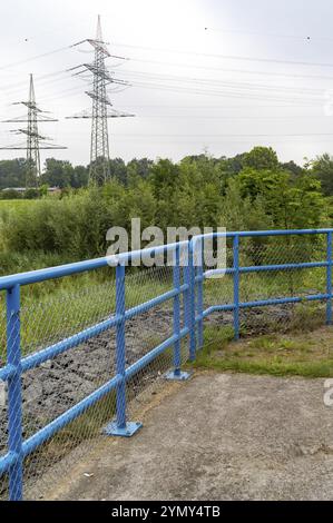 Blue metal railing in front of high voltage pylons Stock Photo