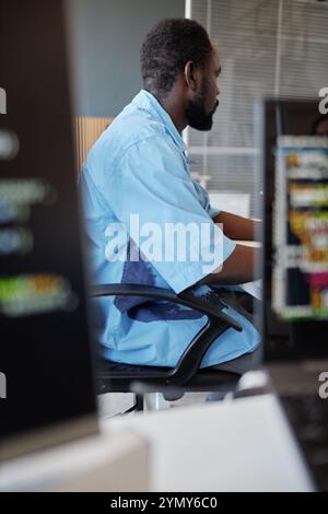 Man sitting in ergonomic chair and focusing on computer screens in a modern workspace. Coding and brainstorming software solutions while surrounded by Stock Photo