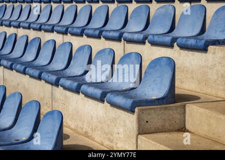 Long rows of blue seats on a sports field stand Stock Photo