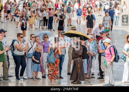 Valletta Malta,Republic Street,group walking tour guide,men women couples families,Franciscan monk friar leading,wearing brown robe,holding umbrella,s Stock Photo