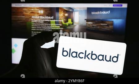 Stuttgart, Germany, 04-28-2024: Person holding smartphone with logo of US software company Blackbaud Inc. in front of website. Focus on phone display Stock Photo