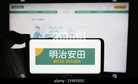 Stuttgart, Germany, 04-12-2024: Person holding cellphone with logo of Japanese business Meiji Yasuda Life Insurance Company in front of business webpa Stock Photo