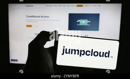 Stuttgart, Germany, 05-27-2024: Person holding mobile phone with logo of American cloud software company JumpCloud Inc. in front of business web page. Stock Photo