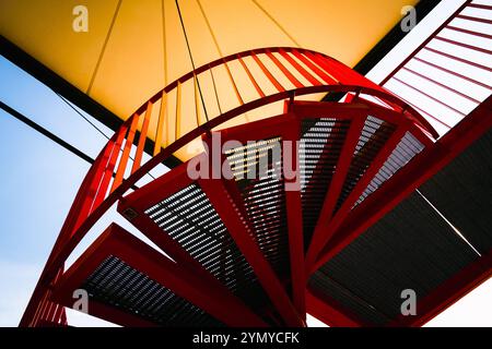 Red Spiral Staircase with Geometric Design Under a Bright Canopy Stock Photo