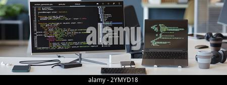 Coding environment featuring code editor open on a desktop monitor with code running on a laptop. Various gadgets including a smartphone, headphones, Stock Photo