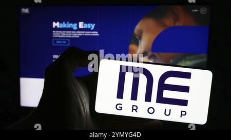 Stuttgart, Germany, 03-25-2024: Person holding mobile phone with logo of British vending machine company ME Group International plc in front of web pa Stock Photo