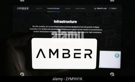 Stuttgart, Germany, 06-13-2024: Person holding cellphone with logo of crypto services company Amber Global Limited in front of business webpage. Focus Stock Photo