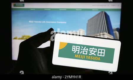 Stuttgart, Germany, 04-12-2024: Person holding smartphone with logo of Japanese business Meiji Yasuda Life Insurance Company in front of website. Focu Stock Photo