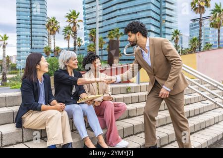 Businessman shaking hands with businesswoman in an outdoor meeting sitting in an outdoor stairs in the financial district Stock Photo