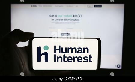 Stuttgart, Germany, 05-17-2024: Person holding cellphone with logo of US financial services company Human Interest Inc. in front of business webpage. Stock Photo