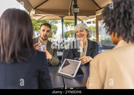 Business team talking and using digital tablet during meeting in a cafeteria Stock Photo