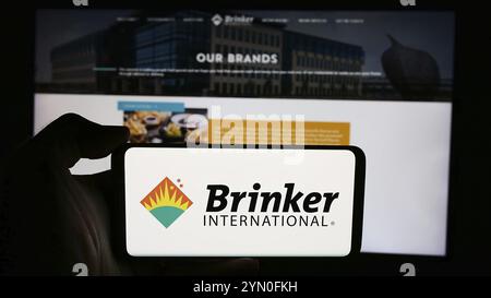 Stuttgart, Germany, 07-05-2024: Person holding cellphone with logo of US hospitality company Brinker International Inc. in front of business webpage. Stock Photo