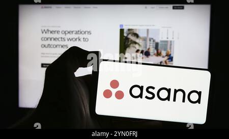 Stuttgart, Germany, 05-27-2024: Person holding mobile phone with logo of American work management software company Asana Inc. in front of web page. Fo Stock Photo