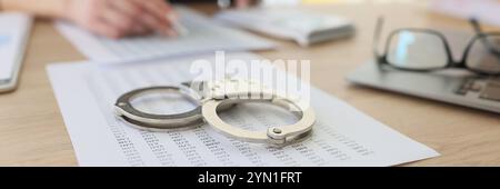 Handcuffs on investigation paper while worker making counts Stock Photo