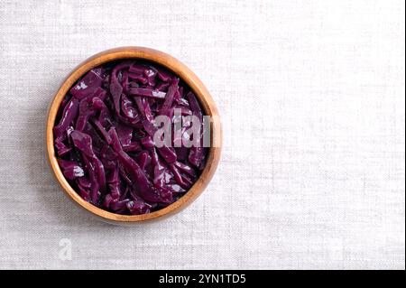 Braised red cabbage in a wooden bowl, with empty space for text. Traditional German side dish of intense purple color made of sliced cabbage. Stock Photo